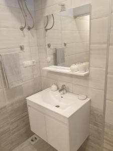 a white bathroom with a sink and a mirror at Stan na dan in Batuša