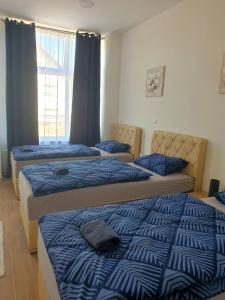 1 dormitorio con 3 camas con edredones azules y ventana en Stan na dan, en Batuša