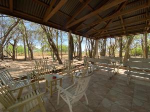 a patio with white chairs and tables and trees at Hotel Campestre Iparoma in Estancia Campo Aroma