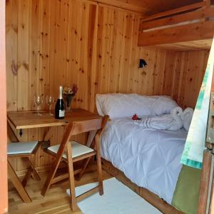 a bed in a wooden room with a table and a table and chairs at Eco Accommodation Cornflower in Craven Arms