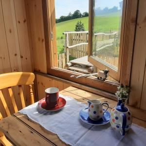 a table with two cups and saucers and a window at Eco Accommodation Cornflower in Craven Arms
