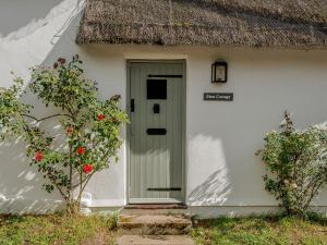 una casa blanca con una puerta verde y un árbol en Eton Cottage, en Farnham