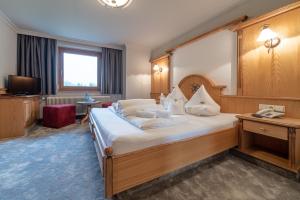 um quarto de hotel com uma cama grande e uma televisão em Burghotel Alpenglühn em Obergurgl