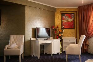 a room with a tv and two chairs and a desk at Hotel Kotva in Bratislava