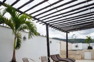 a pergola with chairs and a palm tree on a patio at Terra Inn Hotel Boutique in Guaduas