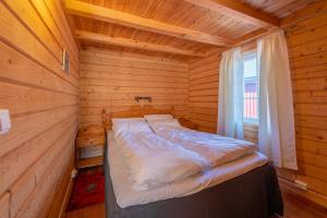 a bed in a wooden cabin with a window at Rorbua Havfruen in Sørvågen