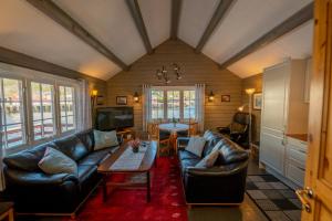 a living room with leather couches and a table at Rorbua Havfruen in Sørvågen