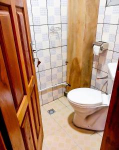 a bathroom with a toilet and a tiled wall at Beautiful- 1 Bedroom Apartment - Parking on site in Douala
