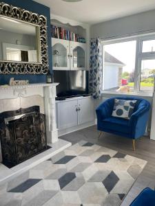 a living room with a fireplace and a blue chair at Fernfield Cottage in Donegal