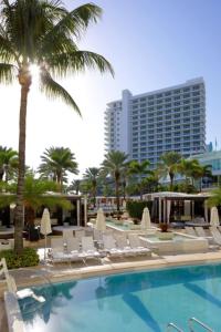une piscine avec des chaises et un palmier ainsi qu'un bâtiment dans l'établissement One-Bedroom Apartment, à Miami Beach