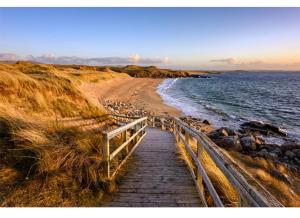 a wooden pathway leading to a beach next to the water at Fernfield Cottage in Donegal