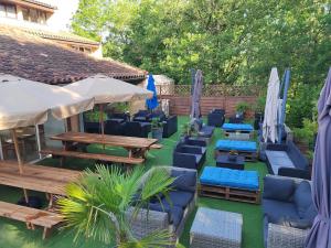 un patio con sedie blu, tavoli e ombrelloni di Village Bord de Ciel a Caylus