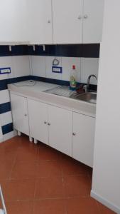 a kitchen with white cabinets and a sink at Nuida Casa Vacanze in Capri