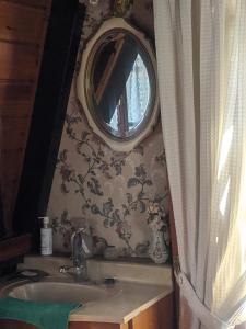 uma casa de banho com um lavatório e um espelho redondo em Habitación Boutique em Villa Alsina