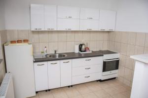 a kitchen with white cabinets and a sink and a refrigerator at Apartman Vesna in Doboj