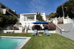 two chairs and an umbrella next to a swimming pool at Villa on Camps Bay Drive in Cape Town
