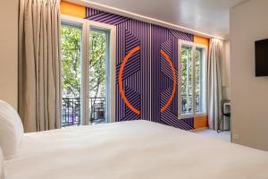 - une chambre avec un grand lit blanc et des fenêtres dans l'établissement Graphik Montparnasse, à Paris