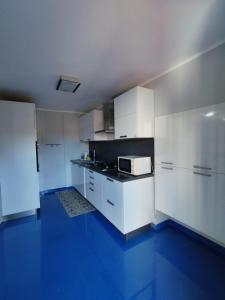 a kitchen with white cabinets and a blue floor at Casa Vacanza "Marinella" in Sulmona
