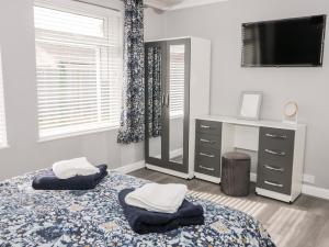 a bedroom with a bed and a dresser and a television at Seaside Retreat in Prestatyn