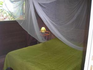 una camera con letto verde e zanzariera di GWAN THAZAR en Guadeloupe a Bouillante