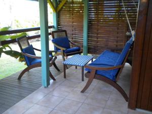 a porch with three chairs and a table and a swing at GWAN THAZAR en Guadeloupe in Bouillante