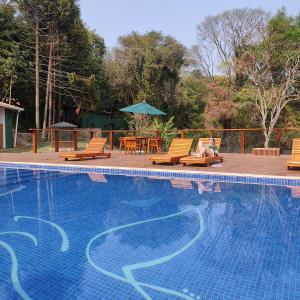 a woman sitting in chairs next to a swimming pool at Encantos do Vale Pousada e SPA Cultural in Bueno Brandão