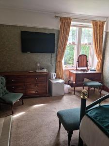 een woonkamer met een flatscreen-tv en een bureau bij St Michaels Guest House in Elgin
