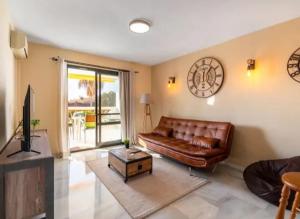 - un salon avec un canapé en cuir brun et une télévision dans l'établissement Pueblo Jardín charming Andalusian complex, à Benalmádena