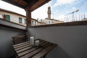 a wooden bench sitting on a balcony with a clock tower at TINA’S APARTMENT in Florence