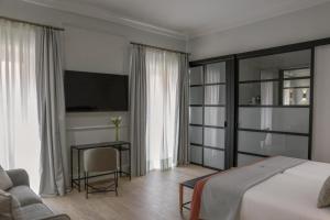 een slaapkamer met een bed, een stoel en een bureau bij Casa Romana Hotel Boutique in Sevilla