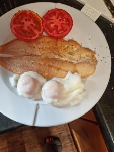 een bord vis en tomaten op een tafel bij St Michaels Guest House in Elgin