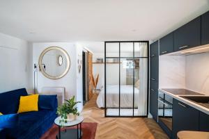 a living room with a blue couch and a bedroom at Charmant Studio paisible dans le Centre du Village in Échenevex