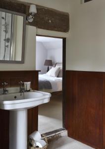 baño con lavabo, cama y espejo en Sign of the Angel, en Lacock