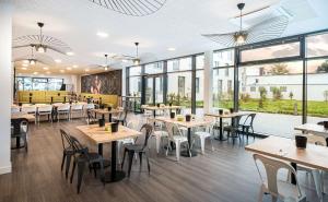 a restaurant with tables and chairs and windows at elaya hotel augsburg in Augsburg
