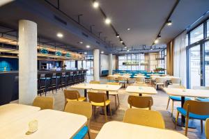 a dining room with tables and chairs and windows at elaya hotel goeppingen in Göppingen