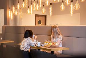 zwei Frauen an einem Tisch in einem Restaurant in der Unterkunft elaya hotel oberhausen in Oberhausen