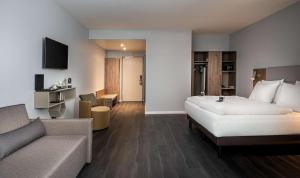 ein Hotelzimmer mit einem großen Bett und einer Couch in der Unterkunft elaya hotel oberhausen in Oberhausen + 31 Fotos