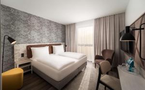 a hotel room with a white bed and a chair at Arthotel ANA Amber in Rostock