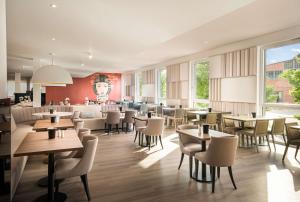 um restaurante com mesas e cadeiras e um bar em Arthotel ANA Amber em Rostock