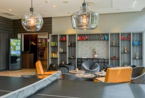 a lobby with chairs and tables and pendant lights at elaya hotel frankfurt oberursel in Oberursel
