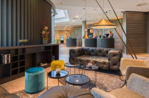 a lobby with a couch and tables and people at elaya hotel frankfurt oberursel in Oberursel