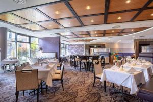 a dining room with tables and chairs with white table cloth at elaya hotel frankfurt oberursel in Oberursel