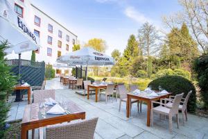 a patio with tables and chairs and an umbrella at elaya hotel frankfurt oberursel in Oberursel