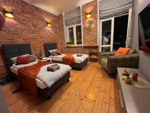 a living room with two beds and a brick wall at Apartament przy Ratuszu in Barczewo