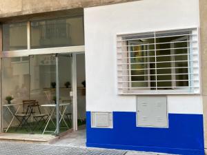 un edificio blanco y azul con una ventana y una mesa en Golondrinas de Malaga "Apartamentos con mucho Arte" y terraza solarium en coliving, en Málaga