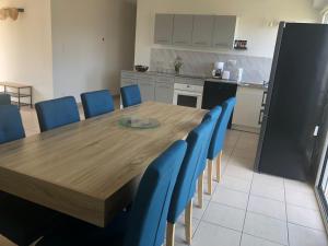 kuchnia z drewnianym stołem i niebieskimi krzesłami w obiekcie Maison plein pied sur les hauteurs de Fécamp w mieście Fécamp