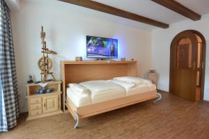 1 dormitorio con 1 cama y TV en la pared en Ferienwohnung Linderspitzblick en Mittenwald