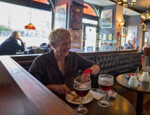 una mujer sentada en un bar con dos copas de vino en Hotel Amager, en Copenhague