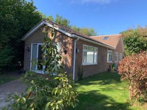 a small brick house with a grass yard at Cheerful 2 Bedroom Bungalow fully Furnished in Bradenham