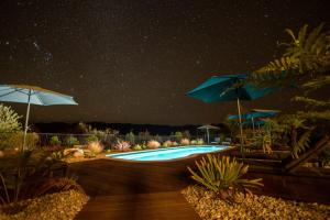 una piscina bajo un cielo estrellado con sombrillas en Kaiteriteri Ridge Holiday Estate, en Kaiteriteri